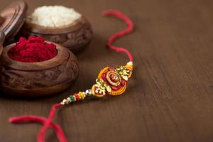 festival indiano raksha bandhan sfondo con un elegante rakhi, chicchi di riso e kumkum. un tradizionale cinturino da polso indiano che è un simbolo di amore tra fratelli e sorelle. foto