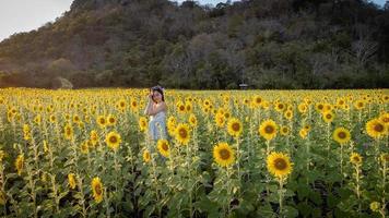 felice gioiosa ragazza asiatica con girasole godersi la natura e sorridere in estate nel campo di girasoli. foto