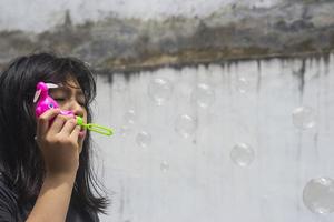 una ragazza che tiene in mano un creatore di bolle e le fa esplodere. foto