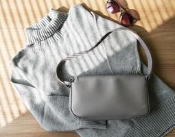 piccola borsa in pelle beige e maglione grigio da donna