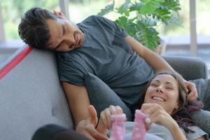 donna incinta sdraiata sul divano con il marito in soggiorno foto