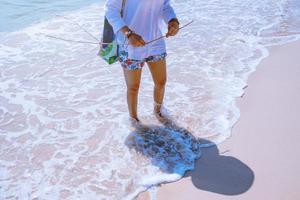 le donne asiatiche viaggiano nella natura. viaggiare rilassati. gioca con l'acqua di mare sulla spiaggia. in estate. Tailandia foto