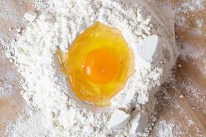 un uovo rotto su un mucchio di farina. preparazione della pasta fatta in casa. foto