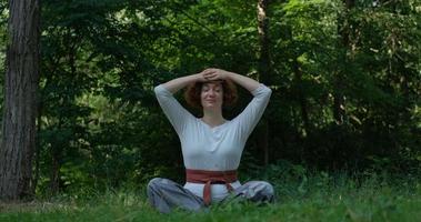 femmina che pratica qigong e meditazione nel parco estivo o nella foresta foto