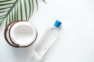 fetta di cocco fresco e bottiglia di olio su sfondo bianco foto