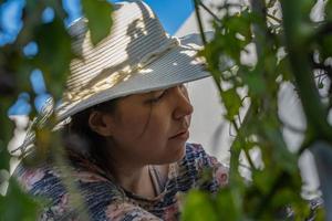 giovane donna con cappello che lavora nel suo orto domestico