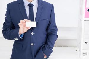 la mano dell'uomo che mostra il biglietto da visita - primo piano girato in ufficio, vuoto, vista dall'alto foto