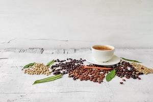 tazza di caffè e chicchi di caffè su fondo di legno bianco foto