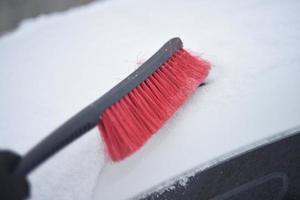 spazzola per auto rossa per pulire la neve in inverno sulla neve foto