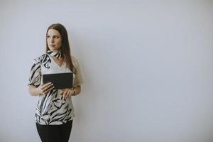 donna d'affari che utilizza tablet digitale vicino al muro in ufficio foto