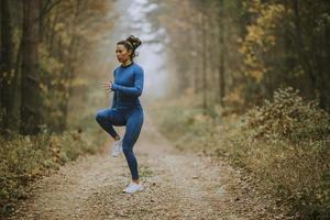 giovane donna che corre facendo esercizio sul sentiero nel bosco in autunno foto