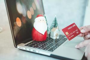 shopping natalizio online a casa con un laptop, decorazioni natalizie babbo natale e albero di natale foto