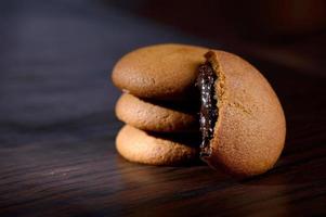 biscotti ripieni di crema al cioccolato. biscotti alla crema di cioccolato. biscotti al cioccolato marrone con ripieno di crema su sfondo nero. foto