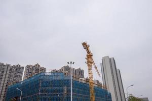 in una giornata nuvolosa, la gru a torre in cantiere è in funzione foto