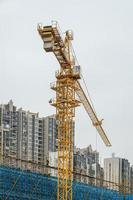 in una giornata nuvolosa, la gru a torre in cantiere è in funzione foto