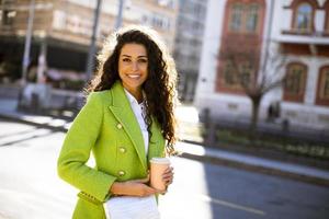 giovane donna che tiene il caffè da asporto per strada foto