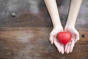 la mano della donna tiene il concetto di cuore rosso, amore e assistenza sanitaria foto