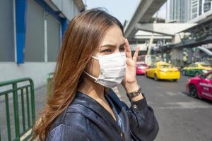 bella donna che indossa una maschera antipolvere protegge l'inquinamento atmosferico e pm 2.5 sulla città di strada
