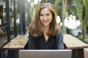 la femmina asiatica intelligente sta lavorando con il computer portatile foto