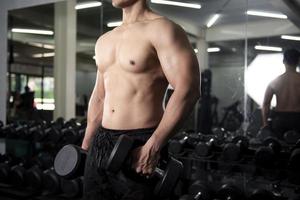 bodybuilder uomo fitness muscolare è allenamento con manubri in palestra
