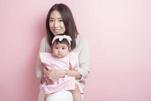 la madre asiatica e l'adorabile bambina sono felici su sfondo rosa