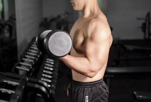 bodybuilder uomo fitness muscolare è allenamento con manubri in palestra foto