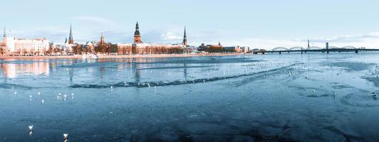 bellissima vista sul fiume ghiacciato con gabbiani seduti sul ghiaccio dal centro storico di riga in lettonia. foto