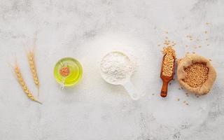 gli ingredienti per l'impasto della pizza fatta in casa con spighe di grano, farina di frumento e olio d'oliva su fondo di cemento bianco. vista dall'alto e copia spazio. foto