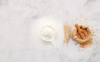 gli ingredienti per l'impasto della pizza fatta in casa con spighe di grano, farina di frumento e olio d'oliva su fondo di cemento bianco. vista dall'alto e copia spazio. foto