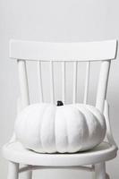 halloween e una zucca bianca su una sedia su sfondo bianco