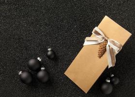 libretto regalo con decorazioni per l'albero di natale su sfondo nero granuloso. volantino con nastro su sfondo nero granuloso foto