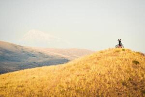 ispirazione smartphone autoscatto ritratto eccitato gioioso caucasico maschio ciclista in piedi di turismo bicicletta guardare per telecamera su superiore cima contento dopo raggiungendo obiettivi In piedi fiducioso godere spensierato foto