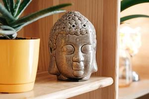 statuetta in ceramica di una testa di buddha su una mensola di legno foto