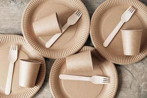 forchette di legno e bicchieri di carta con piatti su fondo di legno