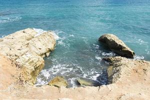 le onde che si infrangono su una spiaggia sassosa, formando uno spruzzo. onde e schizzi sulla spiaggia. onde che si infrangono sugli scogli. foto