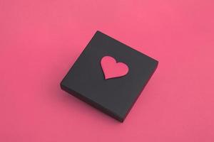 regalo scatola nera con cuori su sfondo rosa. spazio copia primo piano foto