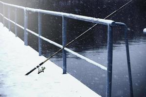 vecchia canna da pesca appoggiata sul corrimano in inverno foto