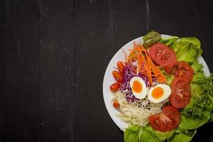 insalata di verdure su fondo di legno nero foto