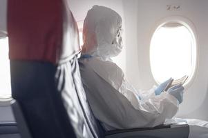 un uomo asiatico indossa tuta protettiva, tuta dpi in aereo, concetto di viaggio di sicurezza. foto
