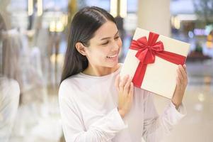 donna che tiene una confezione regalo nel centro commerciale, il ringraziamento e il concetto di natale. foto
