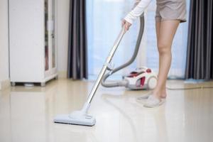 la donna sta pulendo la casa con un aspirapolvere foto