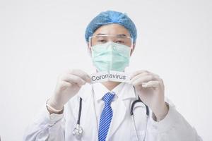 il medico tiene la carta di coronavirus su sfondo bianco