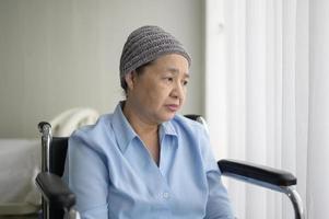 donna asiatica malata di cancro depressa e senza speranza che indossa una sciarpa per la testa in ospedale. foto