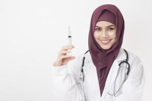 bella donna medico con hijab sta tenendo la siringa su sfondo bianco