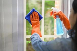 una donna con guanti per la pulizia che usa un disinfettante spray alcolico per pulire la casa, sano e medico, protezione covid-19 a casa concetto foto