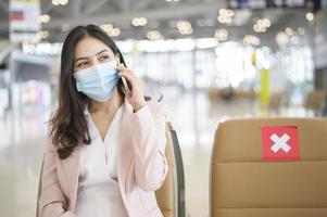 una donna d'affari indossa una maschera protettiva nell'aeroporto internazionale, viaggia sotto la pandemia covid-19, viaggi di sicurezza, protocollo di allontanamento sociale, nuovo concetto di viaggio normale foto