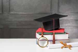 berretto di laurea con libri sulla scrivania bianca, priorità bassa di istruzione foto