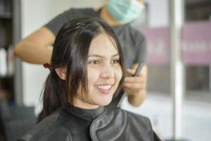 una giovane donna sta ottenendo un taglio di capelli in un parrucchiere, concetto di sicurezza del salone foto