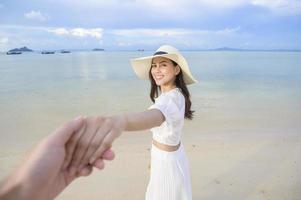 una bella donna felice in abito bianco che si gode e si rilassa sul concetto di spiaggia, estate e vacanze foto