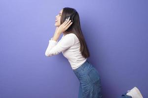 giovane donna sta ascoltando musica su sfondo viola foto